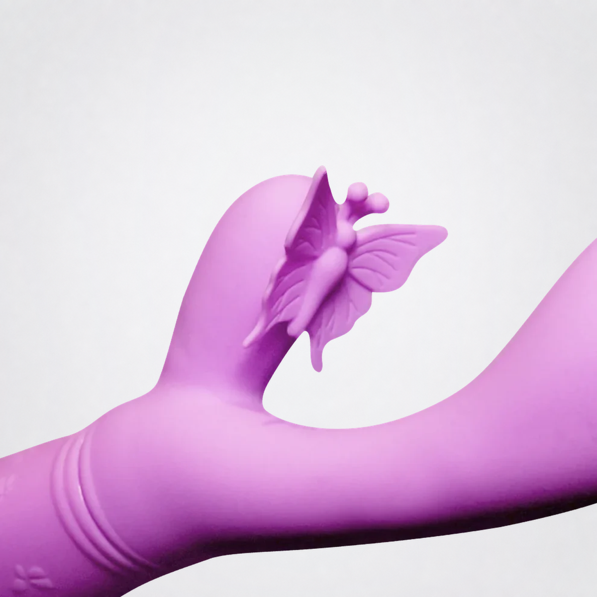 Close-up of the pink Flutter Vibe butterfly attachment on gray