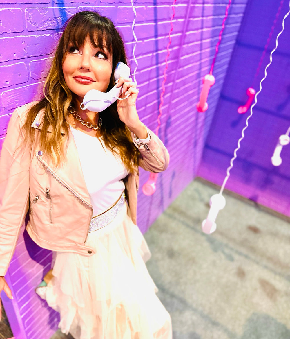 Dana Haines, The Luv Coach, holding a telephone against a purple wall