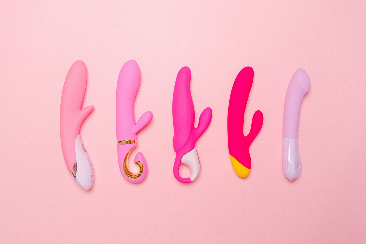 Five pink and purple vibrators arranged on a pink background