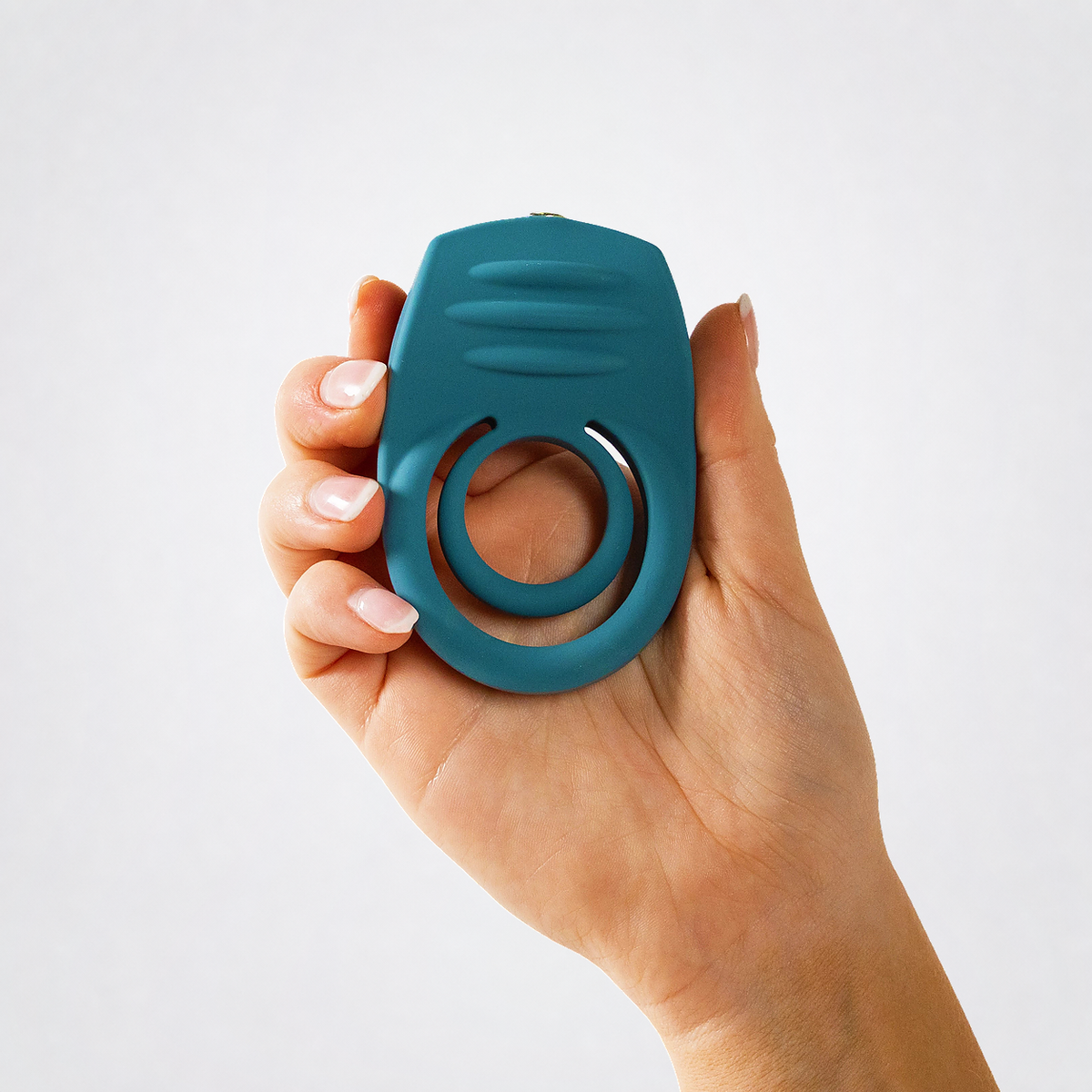 Ring My Bell teal double vibrating C-ring held in one hand on a neutral grey background