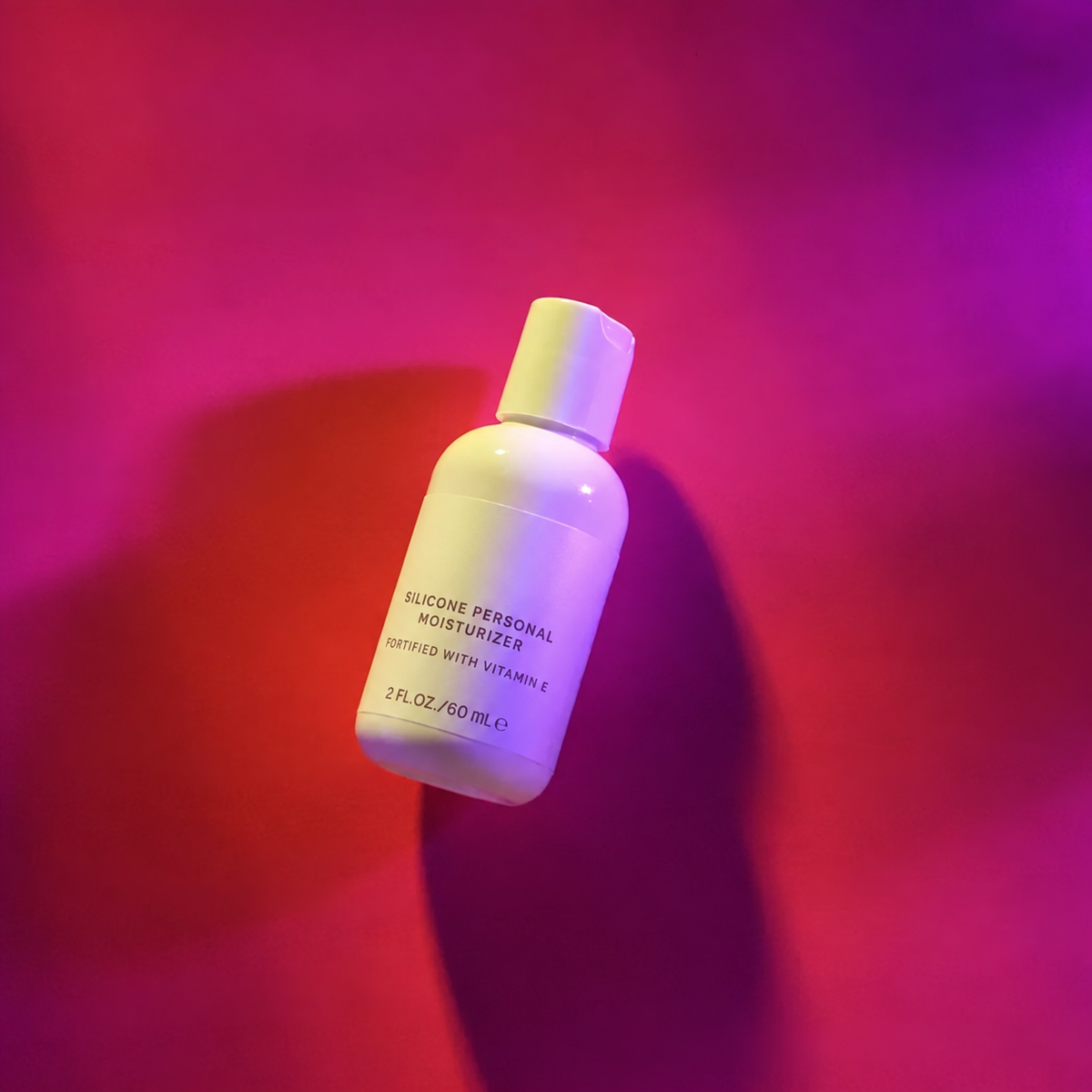 Silicone Deluxe Personal Moisturizer with Vitamin E under colorful lighting