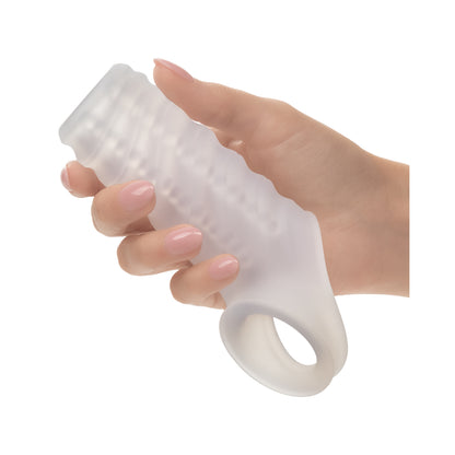 Hand holding the flexible clear Performance Maxx silicone extender sleeve on its original white background