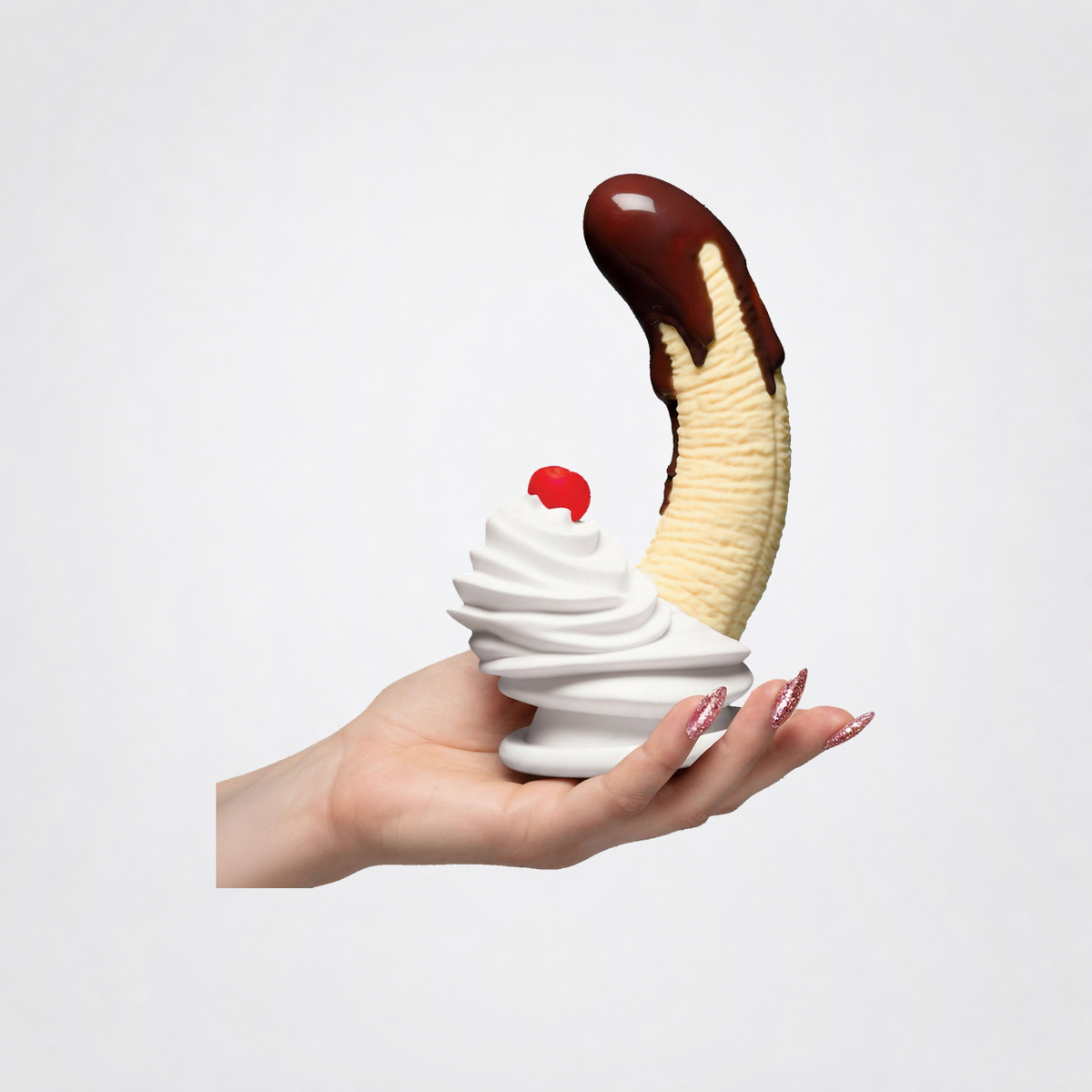 Hand holding the Chocolate Dipped Banana Split dildo for scale on The Luv Coach neutral studio background