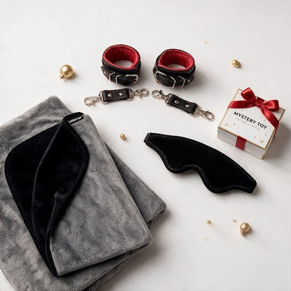 Merry and Wild Kinkmas Box with black and grey Fascinator, leather wrist cuffs, blindfold and mystery toy