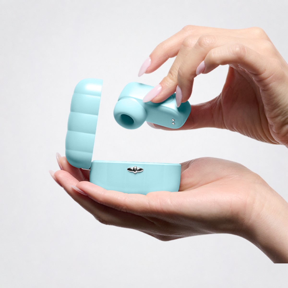 Pleasure Pod Air massager and charging case held in hands on The Luv Coach neutral grey studio background