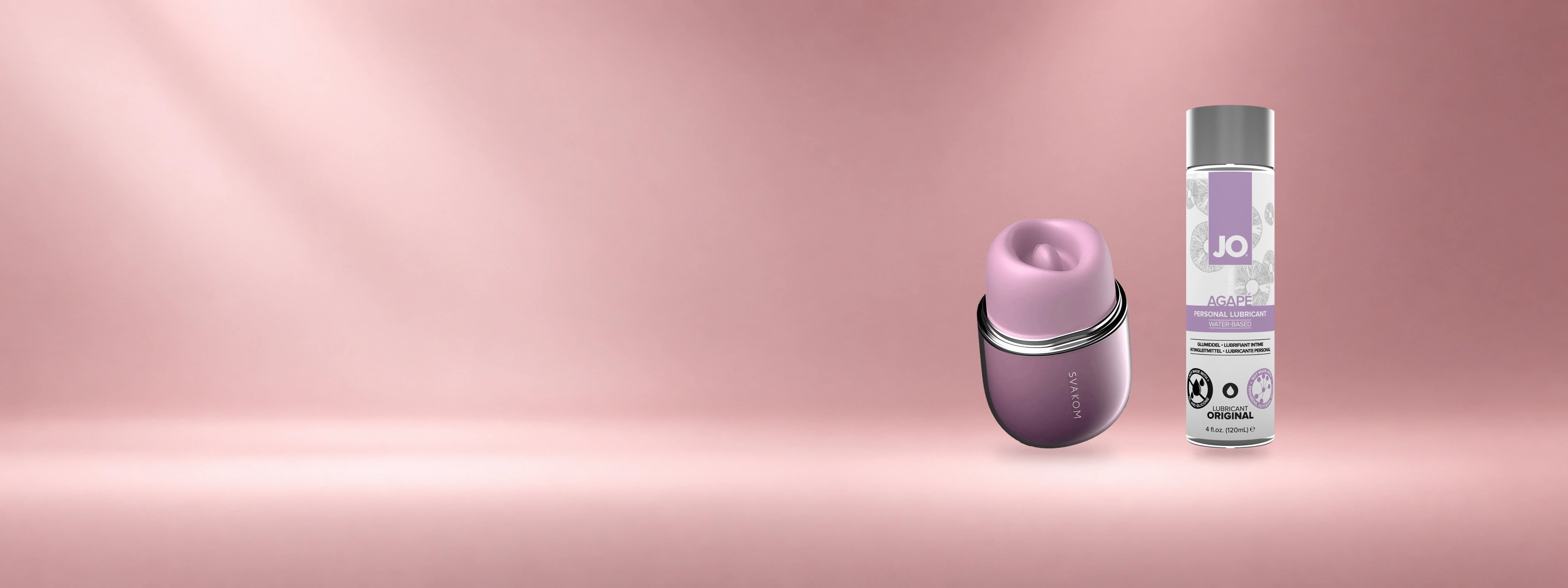 Svakom Klitty and JO Agape personal lubricant displayed on a soft mauve and baby-pink studio background.
